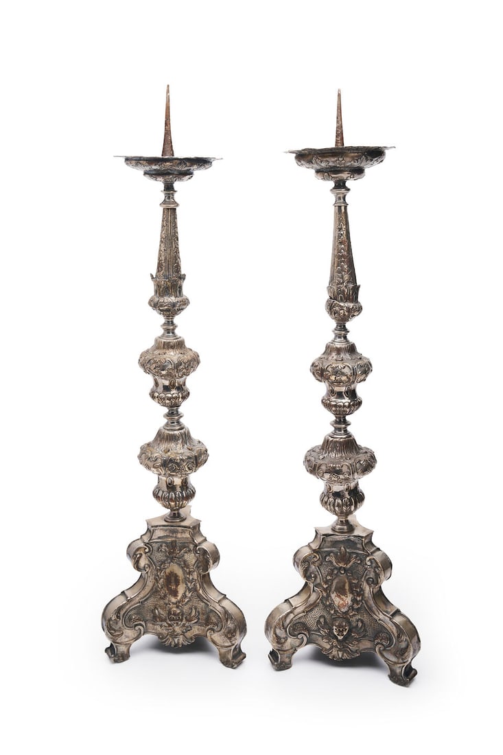 A pair of Baroque-style silvered metal altar candlesticks or prickets Italian, 19th century: A pair of Baroque-style silvered metal altar candlesticks or prickets Italian, 19th century Silvered metal construction with ornate repoussé decoration of winged putti and scrolling foliate desig