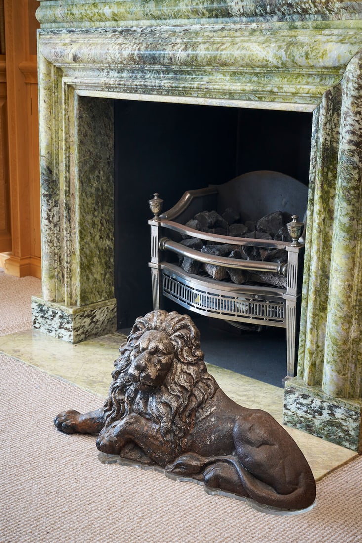 A Victorian flat-back cast iron lion English, 19th century: A Victorian flat-back cast iron lion English, 19th century in recumbent pose, the cast iron surface showing traces of original silvered decoration, traditionally used as a doorstop or boot-scraper, mo