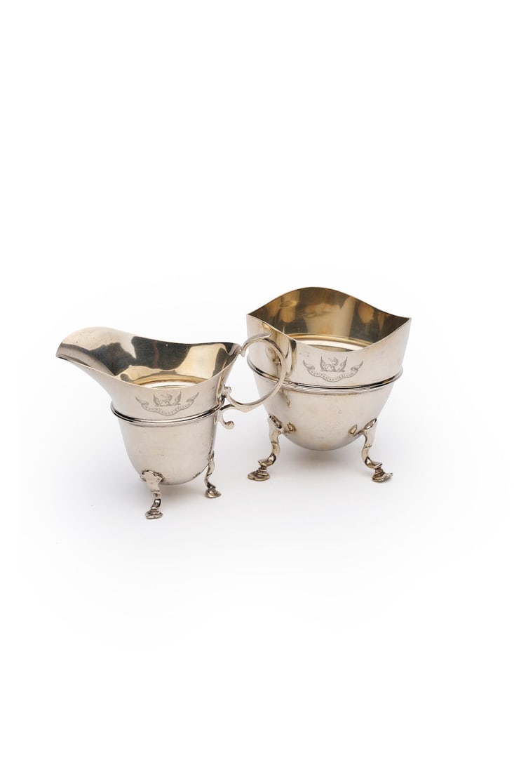 Hardy Brothers Ltd | a sterling silver creamer and sugar bowl marked Hardy Brothers Ltd, London,...: Hardy Brothers Ltd | a sterling silver creamer and sugar bowl marked Hardy Brothers Ltd, London, 1911 Design number 536593 stamped to base, each raised on three shaped feet and engraved with crested m