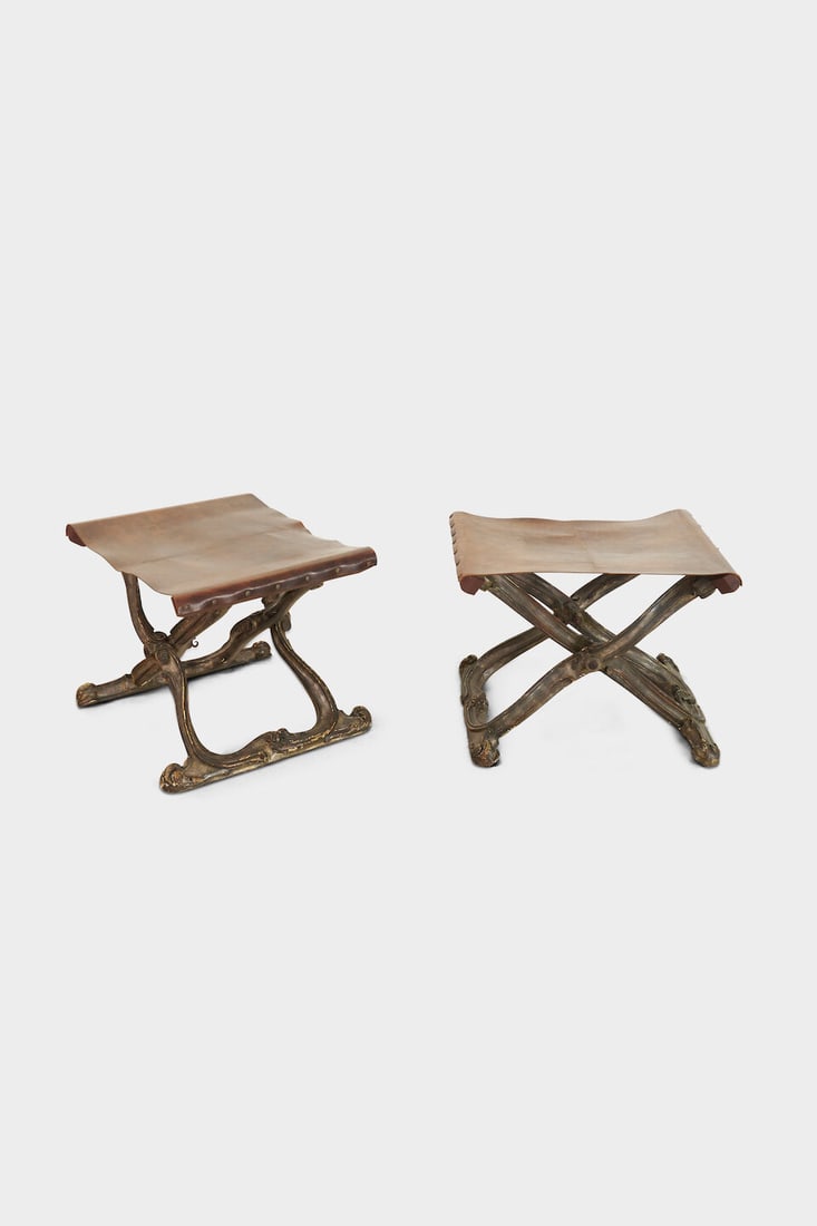 A pair of contemporary Rococo style folding stools,: A pair of contemporary Rococo style folding stools, with parcel silver gilt X frames, tan leather seats, height: 43.0cm, width: 59.5cm, depth: 48.0cm This lot is subject to the following lot symbols: 
