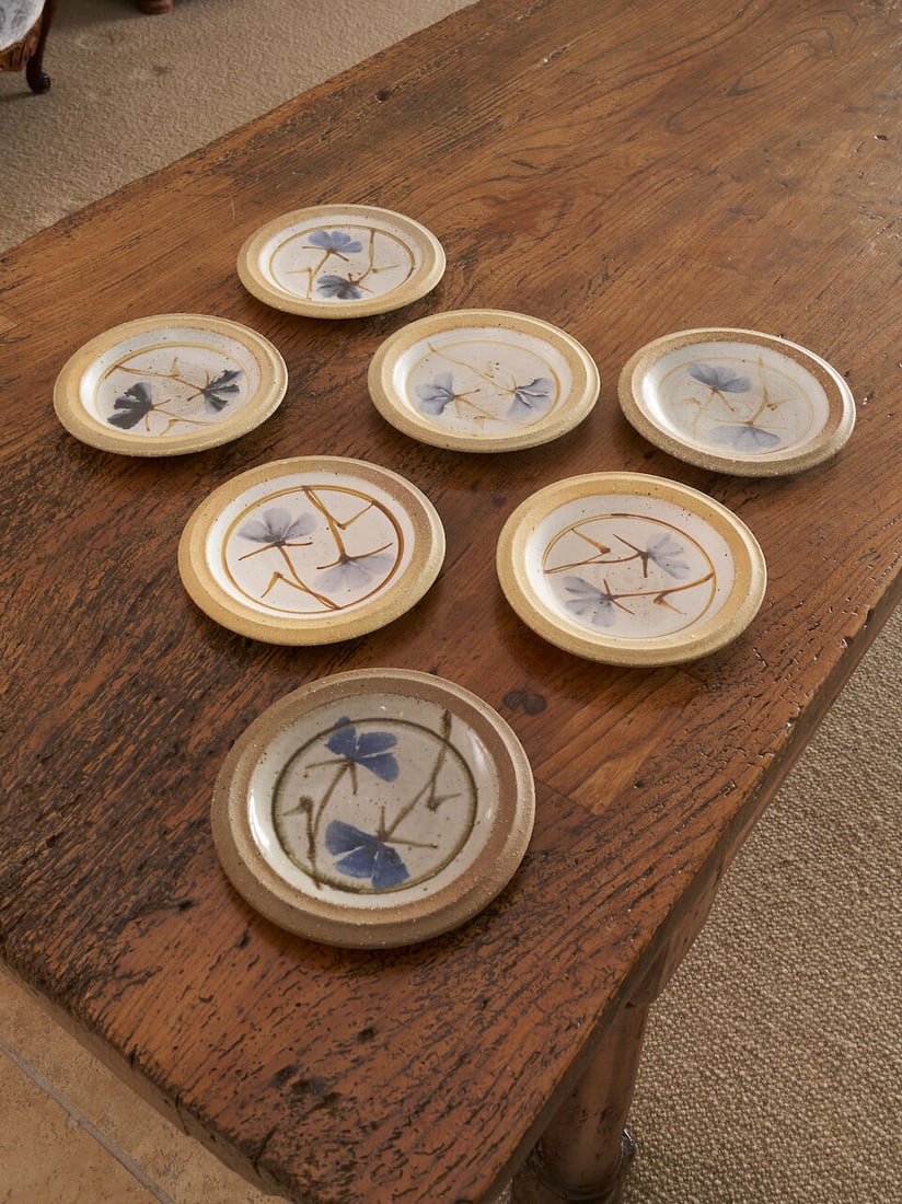 Milton Moon | A set of seven floral studio ceramic plates Australian, circa 1980: Milton Moon | A set of seven floral studio ceramic plates Australian, circa 1980 Each wheel-thrown plate decorated with a pair of stylised blue irises and incised with the artist's initial 'M' on base