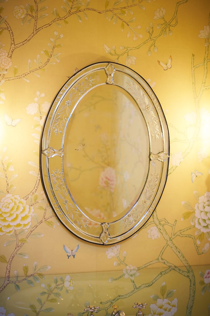 A near pair of Venetian mirrors height: 78.0cm, width: 58.0cm approximately: A near pair of Venetian mirrors oval form with etched foliate designs and bevelled borders, secured by four shaped glass crests, height: 78.0cm, width: 58.0cm approximately Footnotes: Acquired