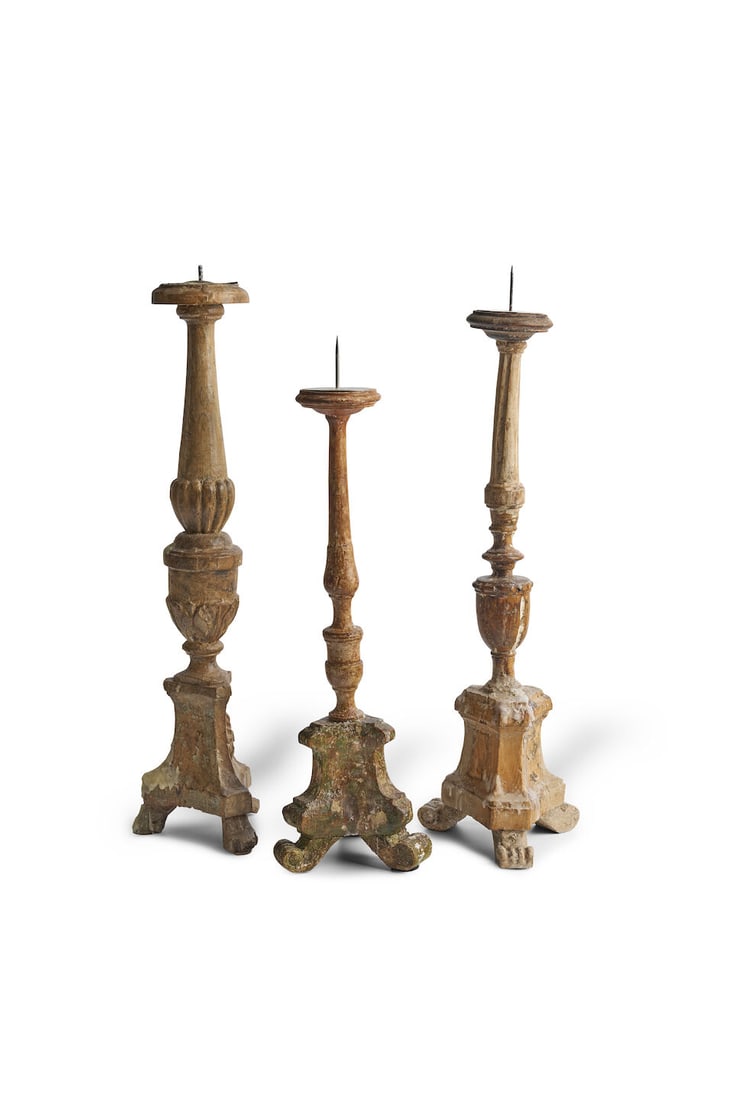A group of three candlesticks,: A group of three candlesticks, carved wood with remnants of pigments, heights: 57.0cm, 54.0cm, 46.0cm For further information on this lot please visit Bonhams.com For further information about this