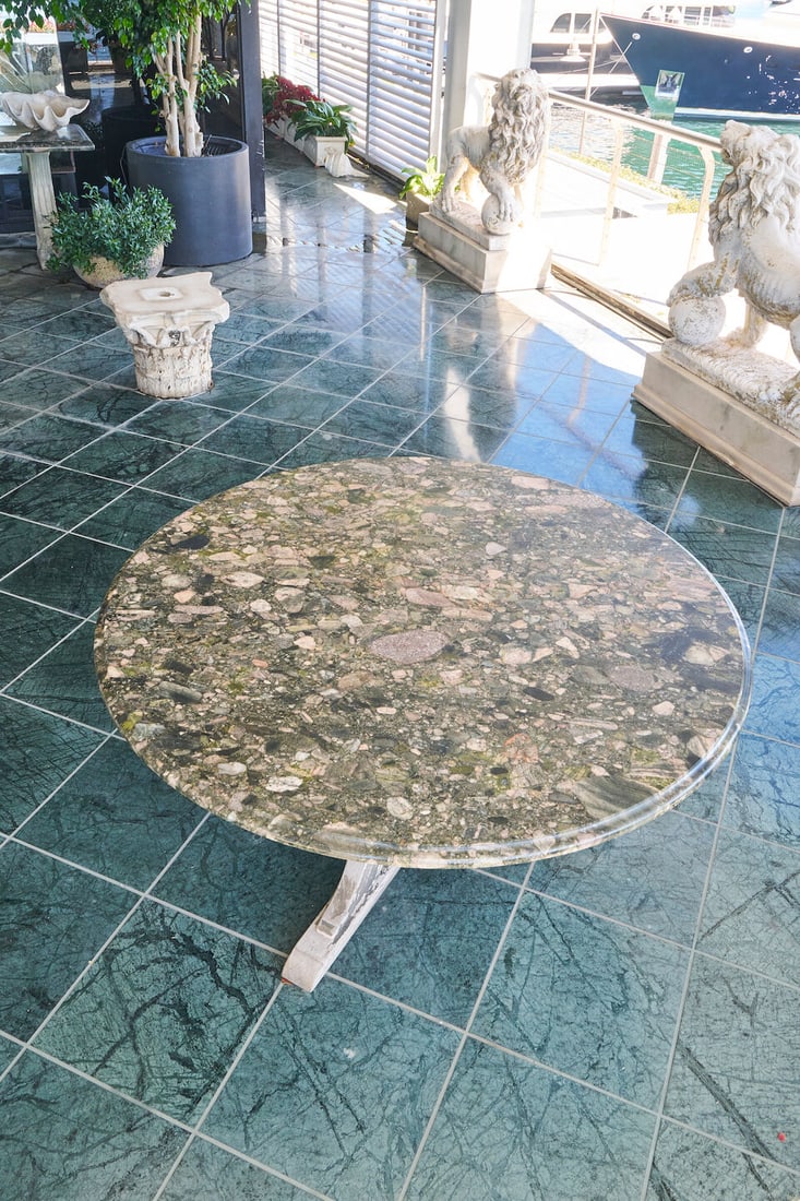 A circular garden table with Verde Marinace granite top,: A circular garden table with Verde Marinace granite top, supported by a trefoil base of weathered hardwood, height: 73.0cm, diameter: 137.0cm This lot is subject to the following lot symbols: W TP W P