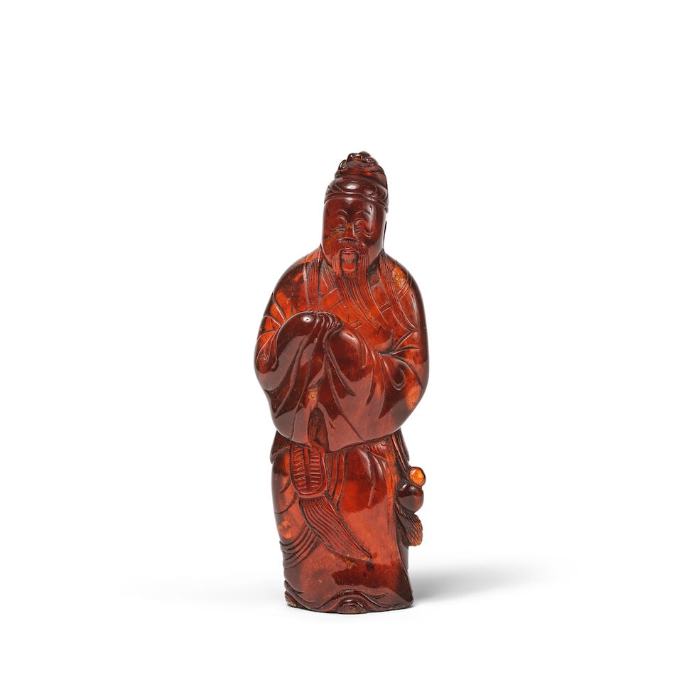 STATUETTE D'UN LETTRÉ EN AMBRE SCULPTÉ Dynastie Qing, XIXe siècle: STATUETTE D'UN LETTRÉ EN AMBRE SCULPTÉ Dynastie Qing, XIXe siècle A CARVED AMBER FIGURE OF A SCHOLAR Qing Dynasty, 19th century The translucent amber a deep honey tone with fine