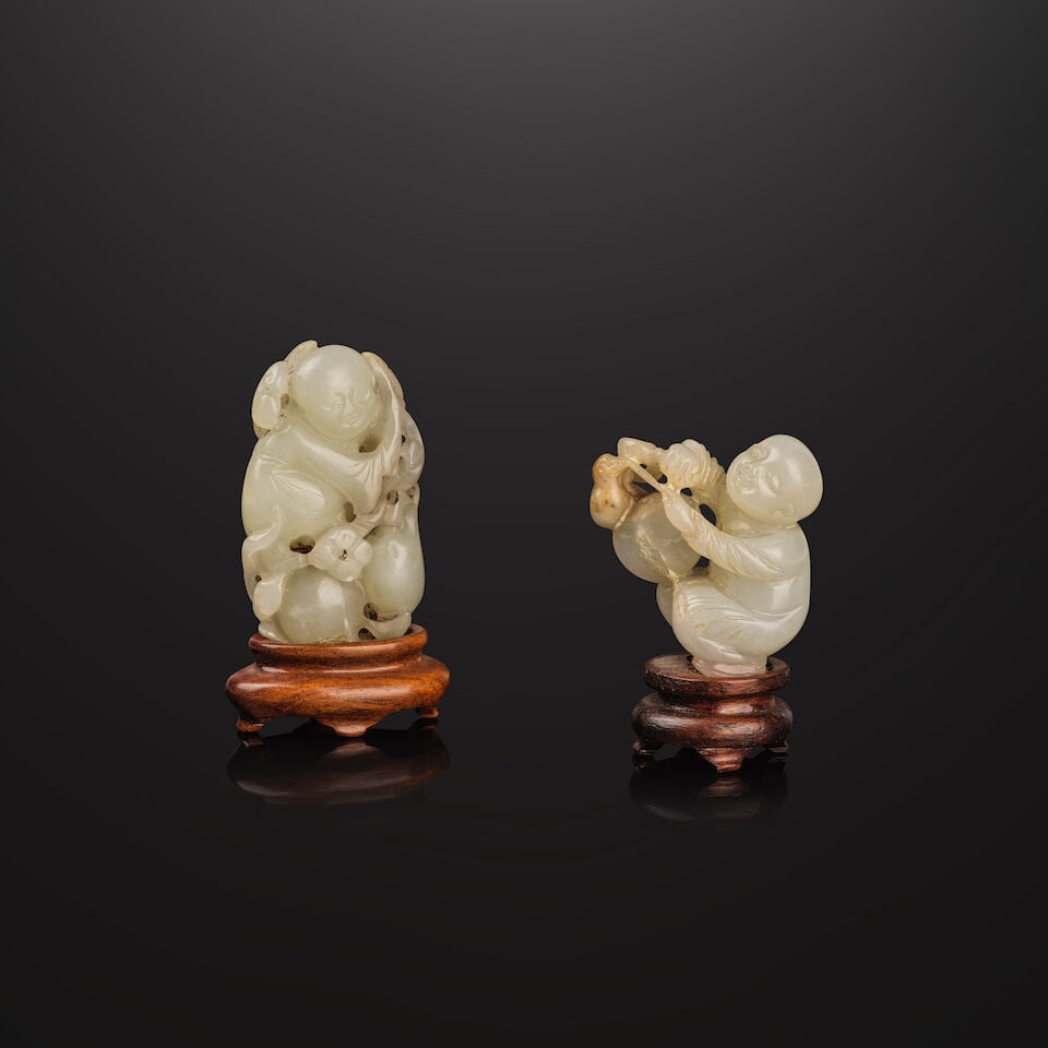 DEUX PETITS SUJETS EN JADE CÉLADON PÂLE Dynastie Qing, XVIIIe siècle (4): DEUX PETITS SUJETS EN JADE CÉLADON PÂLE Dynastie Qing, XVIIIe siècle TWO SMALL PALE CELADON JADE 'BOY' GROUPS Qing Dynasty, 18th century Each with a wood stand 4 cm (1 5/8 in.) and 5