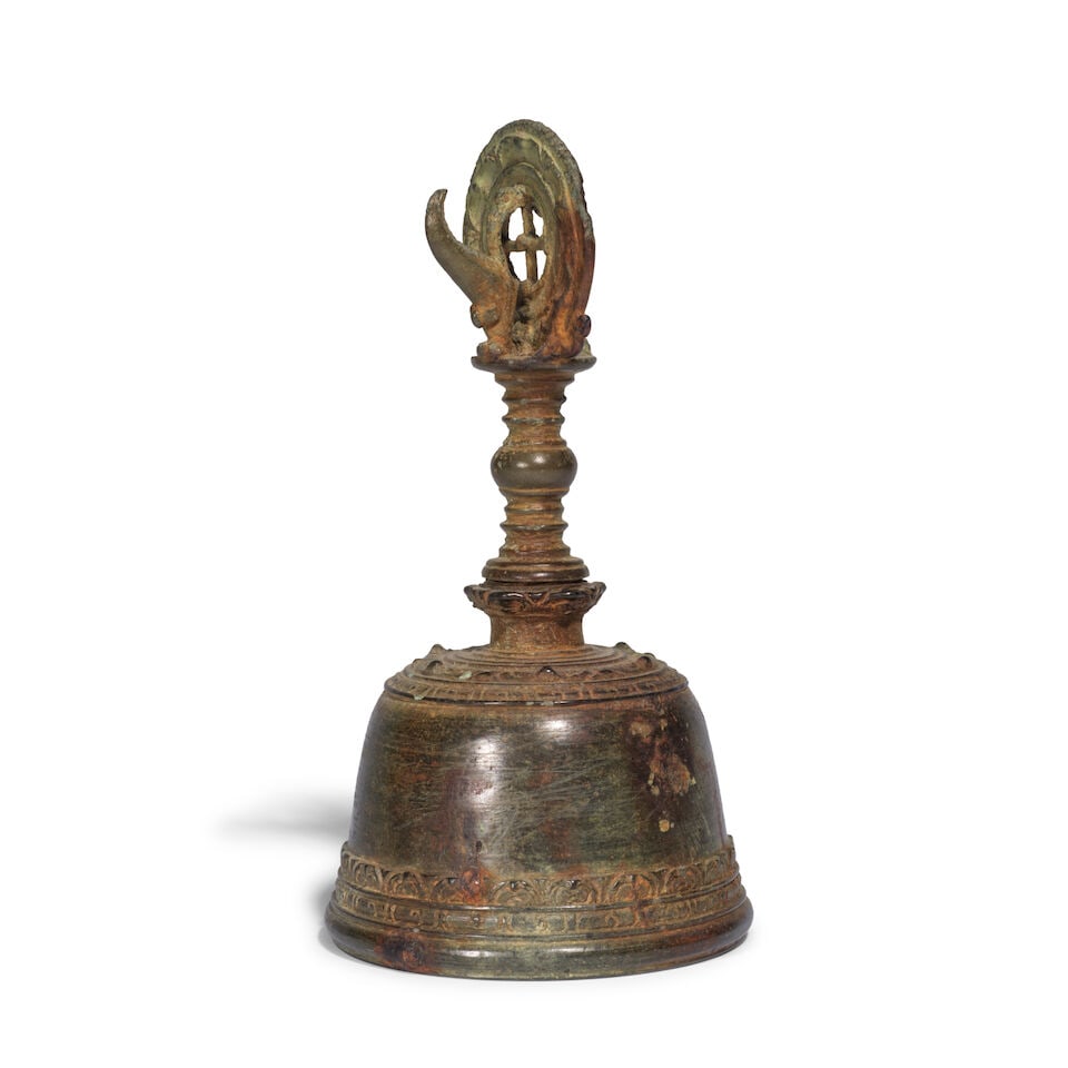 CLOCHE RITUELLE EN BRONZE Indonésie, Java, XIe siècle: CLOCHE RITUELLE EN BRONZE Indonésie, Java, XIe siècle A BRONZE RITUAL HANDBELL Indonesia, Java, 11th century 18 cm (7 1/8 in.) high Footnotes: Cast with a domed body recalling the form of a 