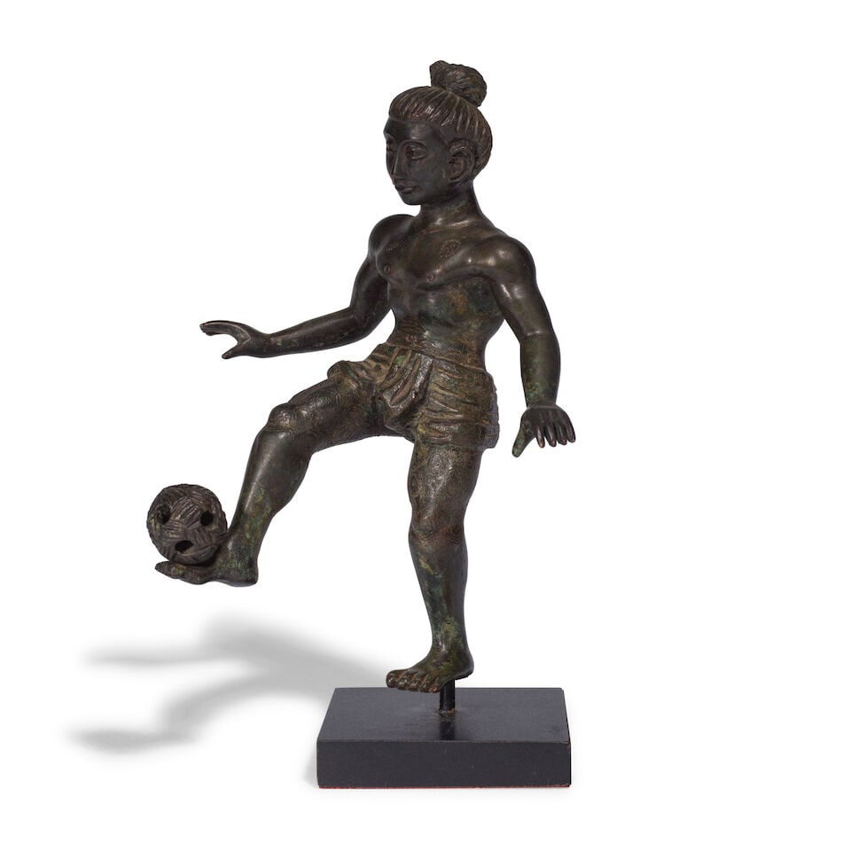 STATUETTE REPRÉSENTANT UN GARÇON JOUANT AU CHINLONE EN BRONZE Birmanie, XIXe siècle: STATUETTE REPRÉSENTANT UN GARÇON JOUANT AU CHINLONE EN BRONZE Birmanie, XIXe siècle A BRONZE FIGURE OF A BOY PLAYING CHINLONE Burma, 19th century 13 cm (5 1/8 in.) high Footnotes: The b