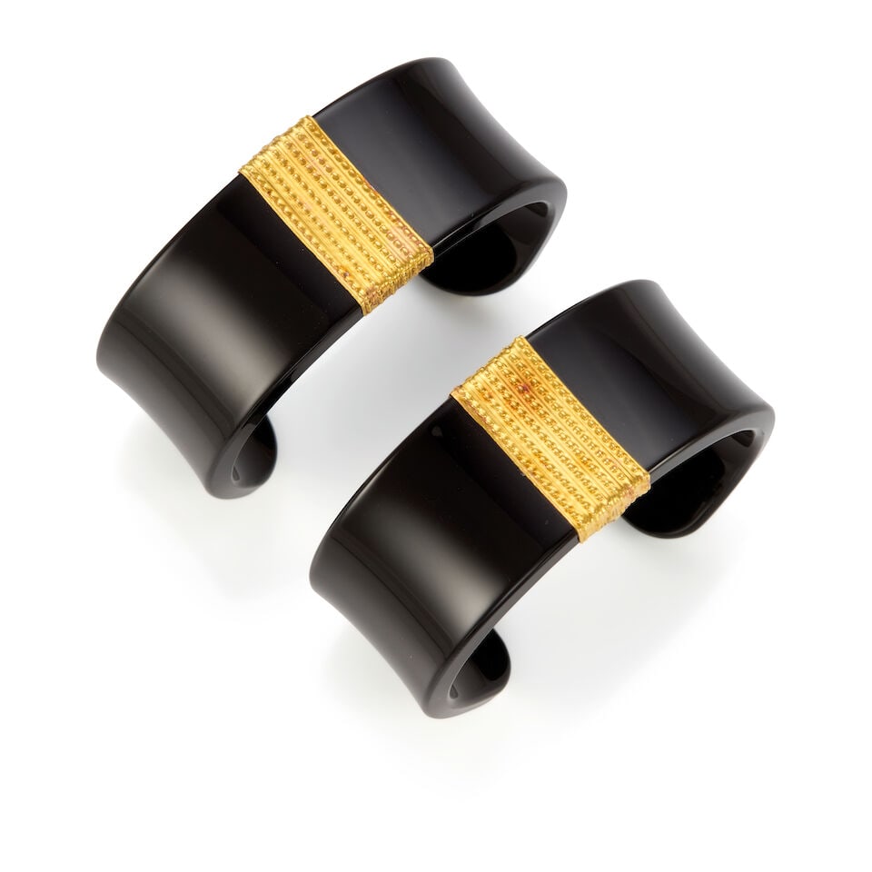 TWO GOLD AND RESIN CUFFS: TWO GOLD AND RESIN CUFFS • 22k yellow gold, black resin • Inner circumference without gap 5 1/2 in., gap measures 1 1/4 in. • Estimated gross weight: 58.7 grams Footnotes: Overall
