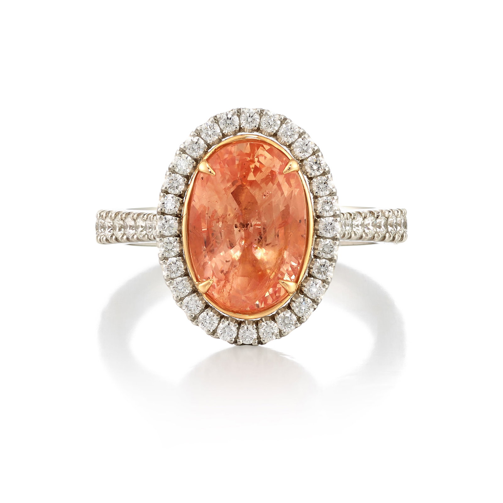 A SAPPHIRE AND DIAMOND RING: A SAPPHIRE AND DIAMOND RING Centering an oval-shaped, pinkish orange sapphire, weighing 5.04 carats, in a surround of round brilliant-cut diamonds; estimated total diamond weight 1.00 carat; mounted i