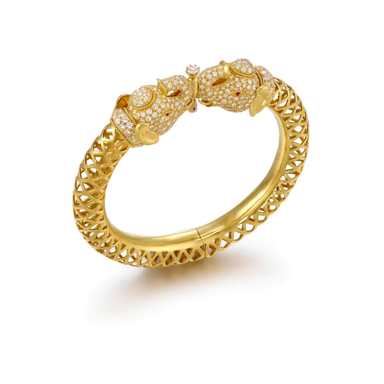A 21K GOLD, DIAMOND AND RUBY BRACELET: A 21K GOLD, DIAMOND AND RUBY BRACELET A hinged bangle, designed with elephant head terminals accented with round brilliant-cut diamonds; inscribed with maker's mark; estimated total diamond weight 4.5