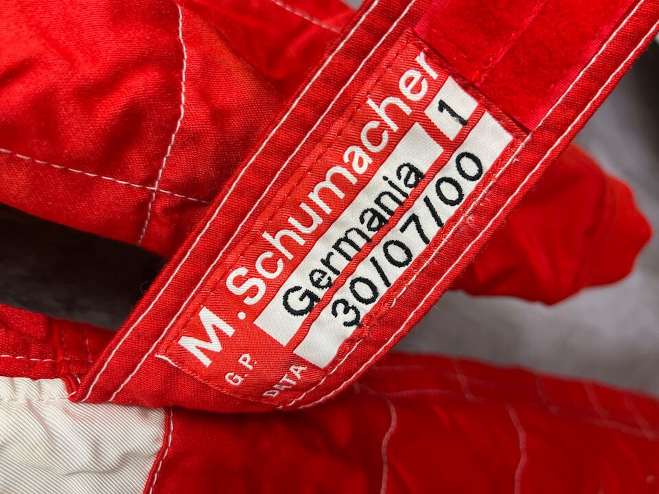 Michael Schumacher's Scuderia Ferrari 2000 German Grand Prix overalls,: First Championship Year with Scuderia Ferrari Michael Schumacher's Scuderia Ferrari 2000 German Grand Prix overalls, in red and white, with sponsors logos, signed to the chest in black marker, the