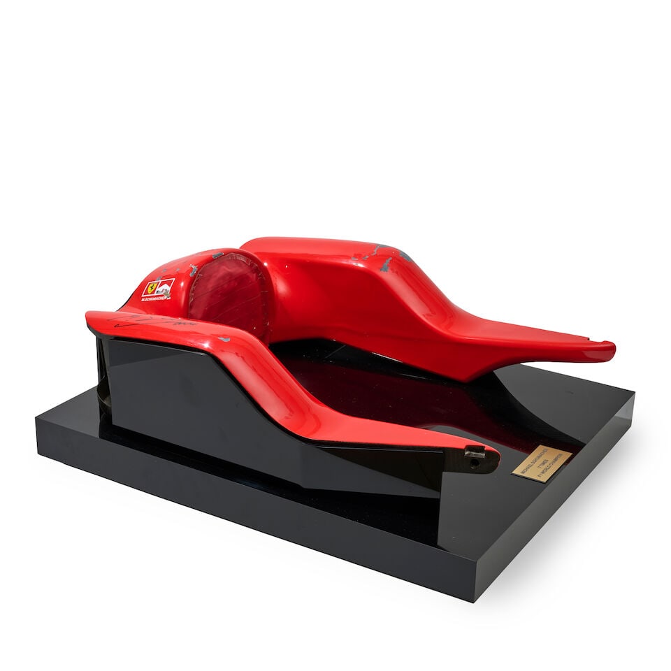 A Scuderia Ferrari F2004 F1 headrest signed by Michael Schumacher,: A Scuderia Ferrari F2004 F1 headrest signed by Michael Schumacher, carbon fibre construction, painted red with sponsors logos, signed by Schumacher to drivers right side in black marker, with