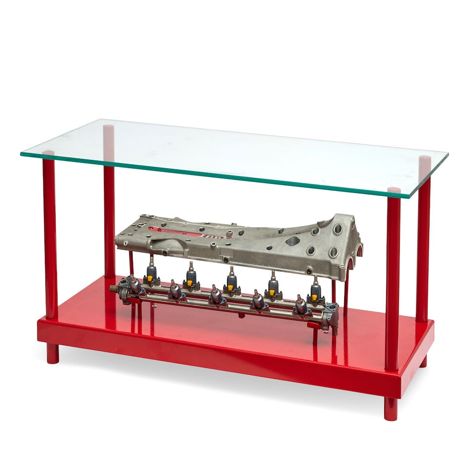 A Ferrari valve cover coffee table, signed by Michael Schumacher,: A Ferrari valve cover coffee table, signed by Michael Schumacher, valve cover signed by Schumacher in black marker, fitted with stand, to sit within table, loosely mounted with fuel injection