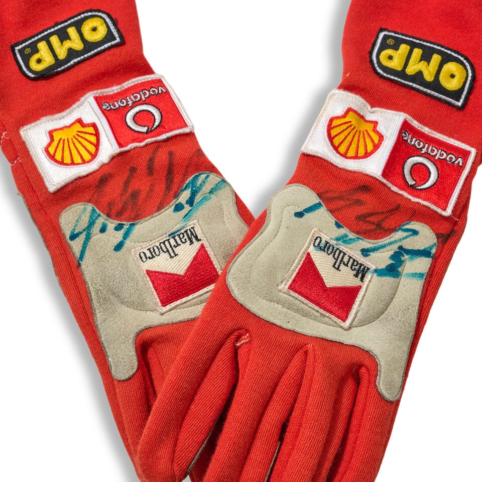 A signed pair of Michael Schumacher's 2004 Scuderia Ferrari used gloves,: A signed pair of Michael Schumacher's 2004 Scuderia Ferrari used gloves, by OMP, in red with grey knuckles, sponsors logos, signed to each in blue pen, showing wear from use, both marked 12.10.04 to