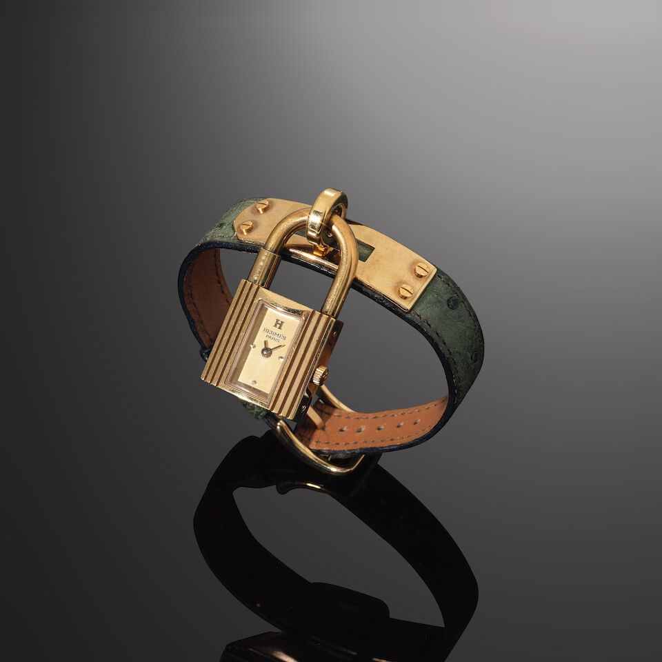 Hermès Paris. Montre Kelly en métal doré et cuir autruche vert. Hermès Paris...: Hermès Paris. Montre Kelly en métal doré et cuir autruche vert. Hermès Paris. Kelly watch in gold-tone metal and green ostrich leather. Cadran doré, mouvement quartz. Golden-t