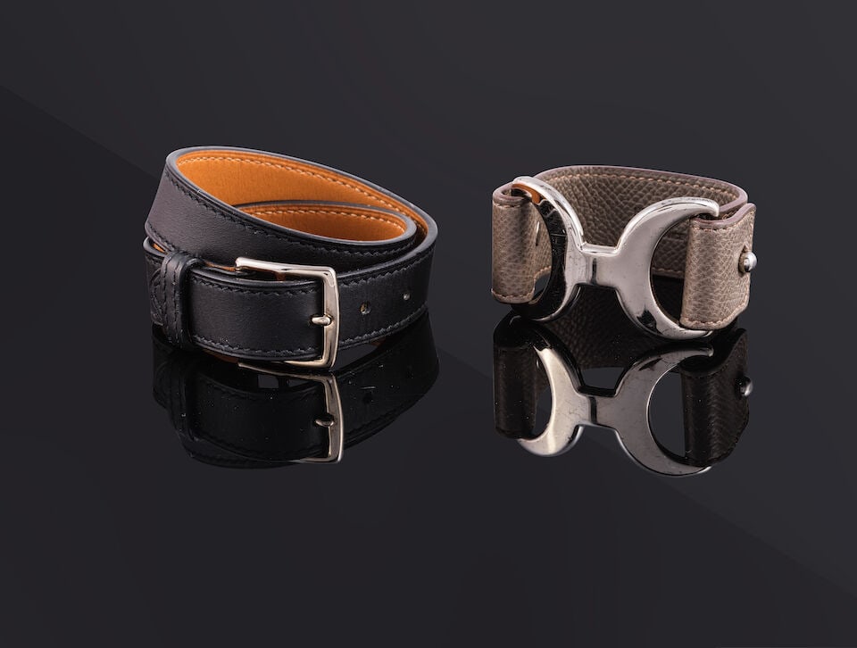 Hermès Paris. Deux bracelets Pavane et Etriers. Hermès Paris. Two bracelets Pavane and...: Hermès Paris. Deux bracelets Pavane et Etriers. Hermès Paris. Two bracelets Pavane and Etriers. Condition grade: B et A. Pavane en cuir Epsom étoupe et Etriers en veau Swift noir. Pavan