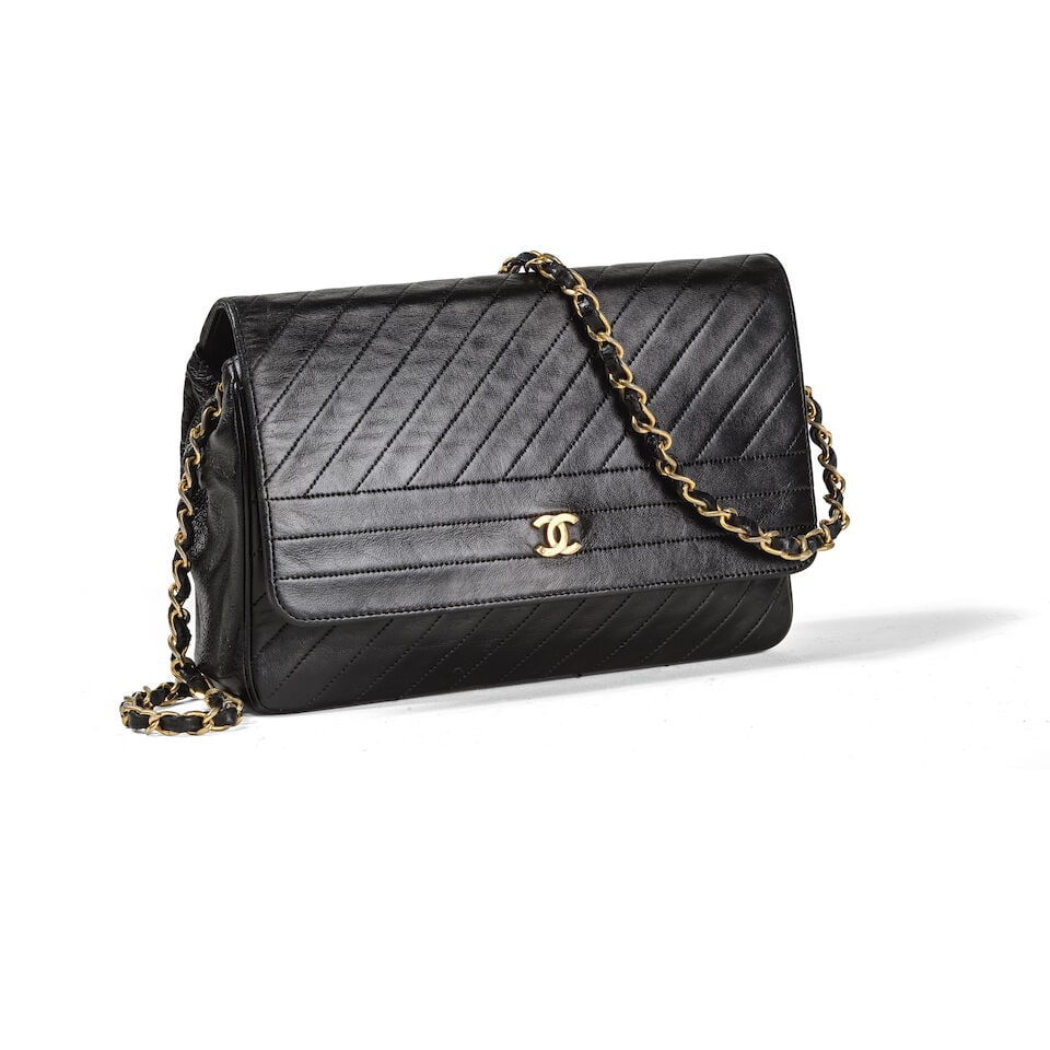 Chanel, circa 1990. Sac en cuir agneau noir à surpiqures diagonales. Chanel, circa 1990. Bl...: Chanel, circa 1990. Sac en cuir agneau noir à surpiqures diagonales. Chanel, circa 1990. Black lambskin leather bag with diagonal stitching. Anse bandoulière entrelacée. Interlaced