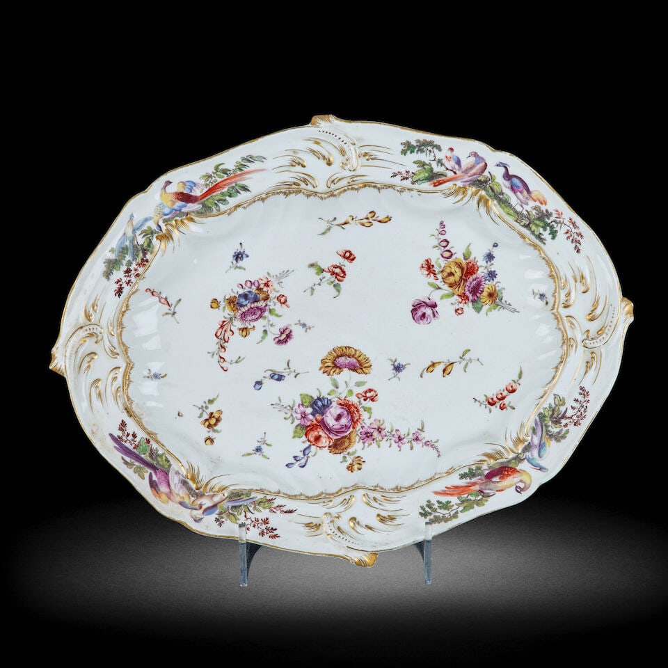 A Chelsea porcelain serving dish Circa 1756-1769: A Chelsea porcelain serving dish Circa 1756-1769 Of shaped oval form, relief moulded with scrolls and painted with floral sprays, gilt scrolls and exotic birds, 41.5cm wide, gold anchor mark For