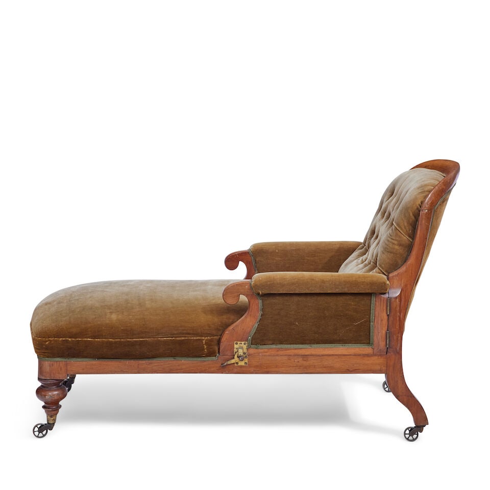A Victorian mahogany daybed Second quarter 19th century: A Victorian mahogany daybed Second quarter 19th century With an upholstered button back, stuff over seat and hinged arms raised on turned legs with brass caps and castors, the rear bearing a paper