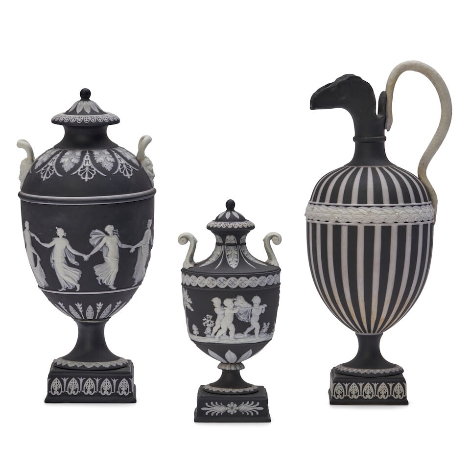 Three Wedgwood Black Jasper Dip Items, England, 19th century,: Three Wedgwood Black Jasper Dip Items, England, 19th century, each with applied white jasper relief, a ewer with vertical engine turning and snake handle, ht. 12; and two covered vases, one with Danci
