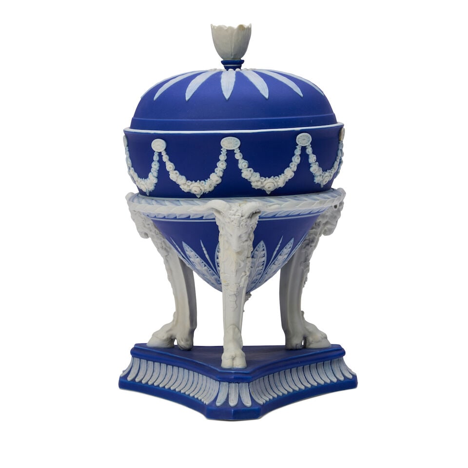 Wedgwood Dark Blue Jasper Dip Tripod Vase and Cover, England, 19th century,: Wedgwood Dark Blue Jasper Dip Tripod Vase and Cover, England, 19th century, floral finial to a domed cover, applied white floral festoons to the bowl set atop goat mask and hoof legs, on a triangular 