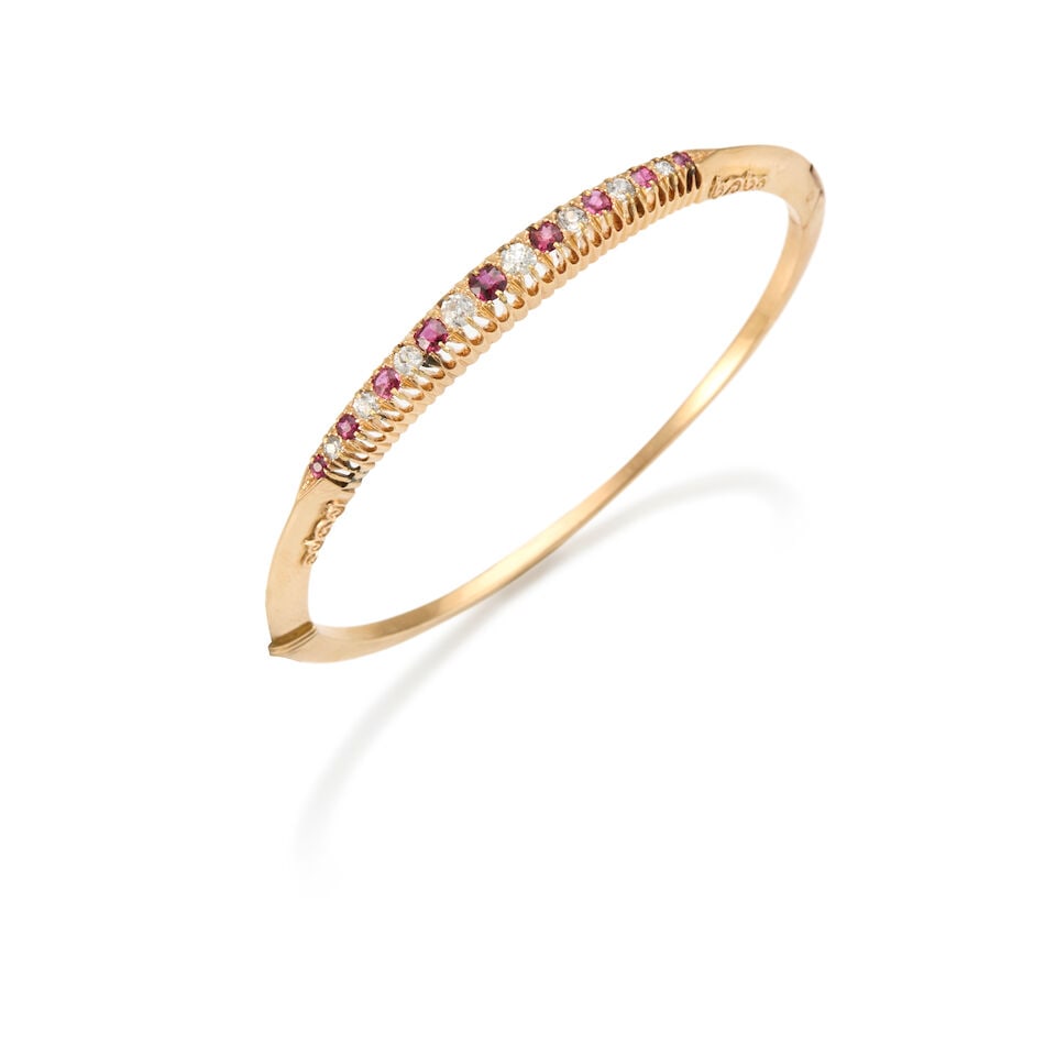 14K GOLD, RUBY, AND DIAMOND BANGLE: 14K GOLD, RUBY, AND DIAMOND BANGLE • 14k yellow gold • Nine round shaped rubies weighing approximately 0.30 carat total • Eight round shaped diamonds weighing approximately 0.30