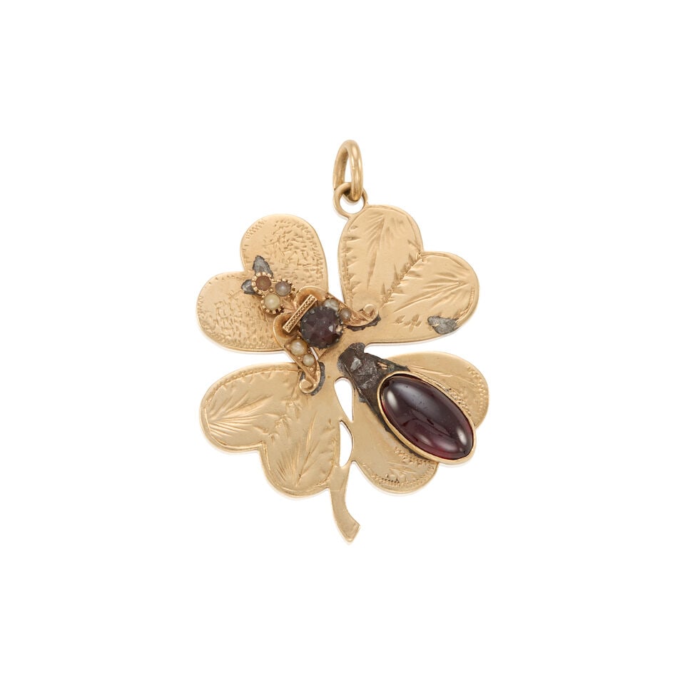 14K GOLD AND GARNET CLOVER CHARM: 14K GOLD AND GARNET CLOVER CHARM • 14K yellow gold • One oval shaped garnet measuring approximately 13.59mm x 7.33mm • One round shaped garnet measuring approximately 5.19mm in