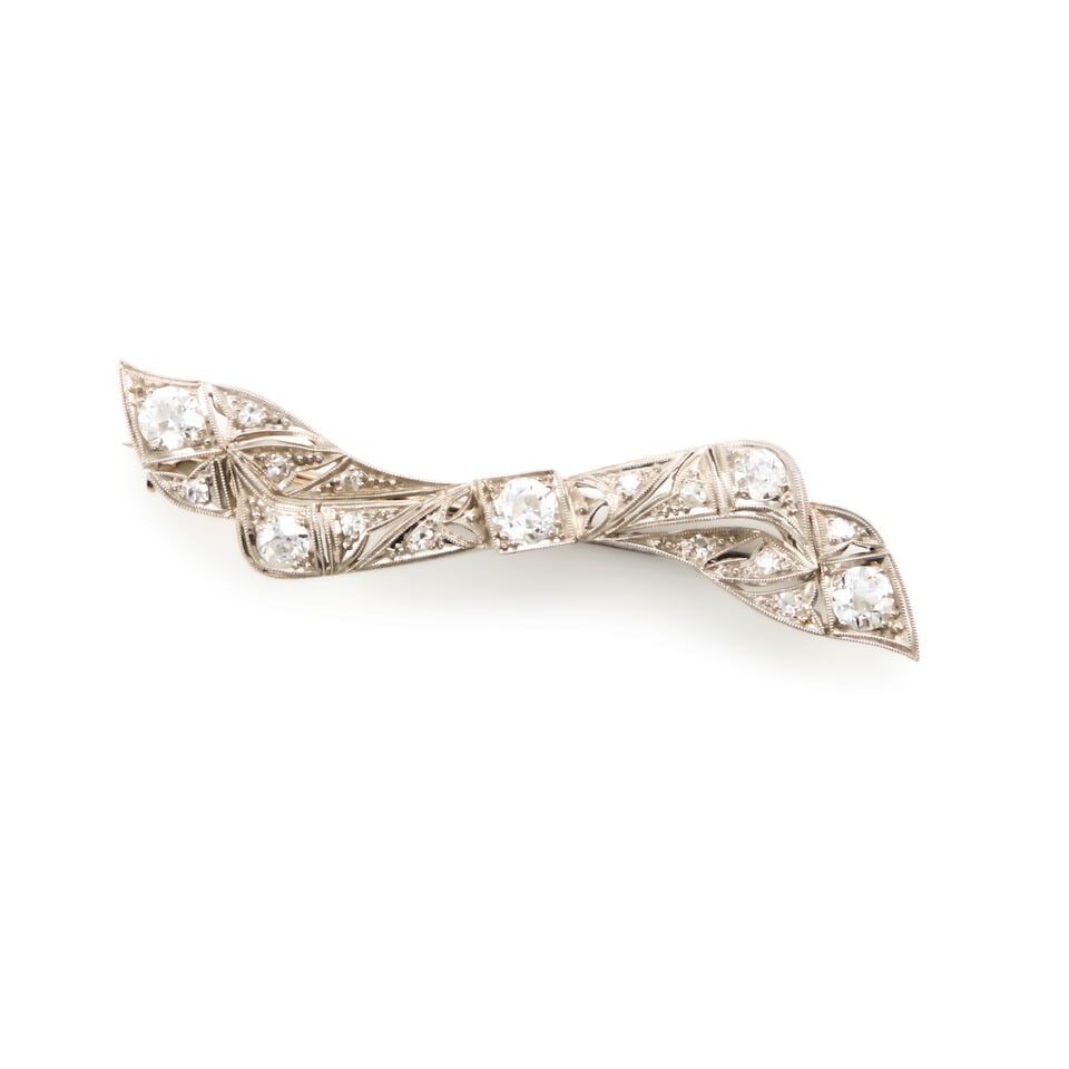 PLATINUM, GOLD AND DIAMOND BOW BROOCH: PLATINUM, GOLD AND DIAMOND BOW BROOCH • Platinum and 14K white gold • Numerous round shaped diamonds weighing approximately 1.50 carat total • Measures 2 1/4 in. x 1/2 in. • Es