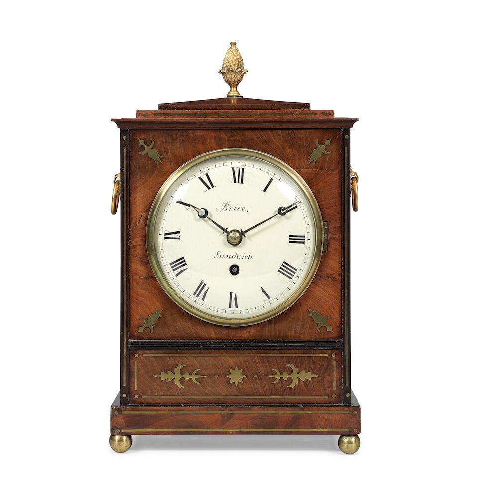 A Regency mahogany and brass inlaid bracket timepiece Brice, Sandwich: A Regency mahogany and brass inlaid bracket timepiece Brice, Sandwich The case sumounted by a brass pineapple finial over a sloped top with moulded brass inlay to a shallow moulded surround, the