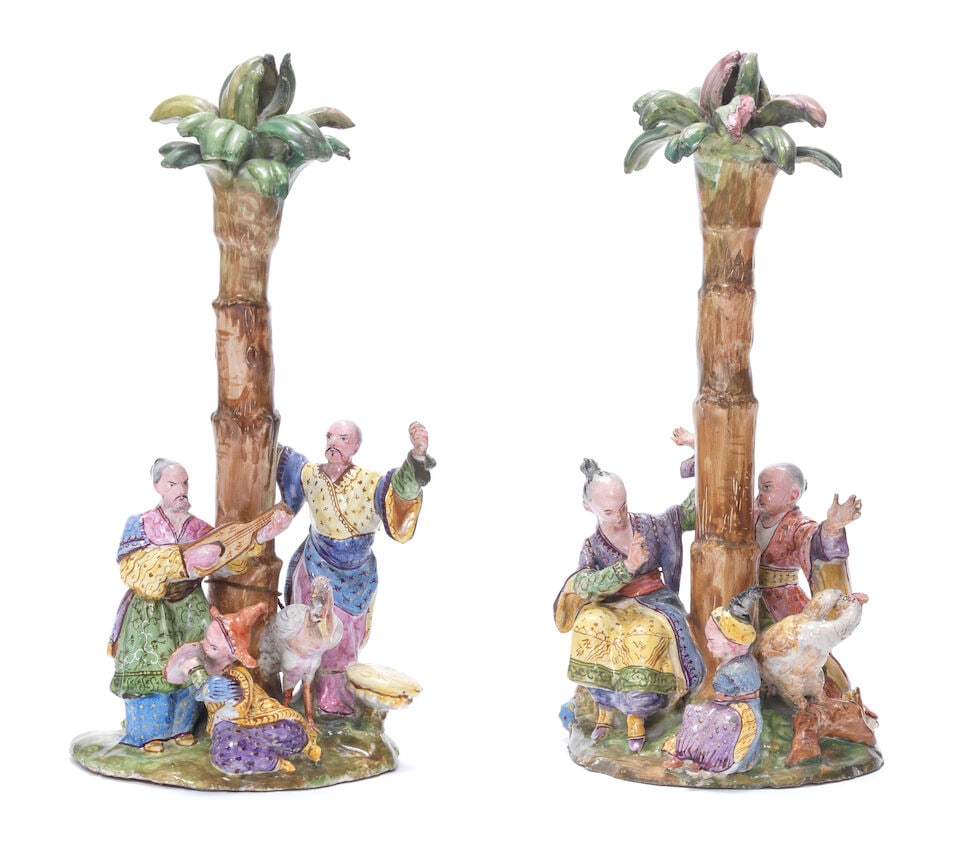A pair of European faience chinoiserie groups, 19th century: A pair of European faience chinoiserie groups, 19th century Each modelled with three chinoiserie figures and a stork and cockerel, respectively, around a palm tree, their costumes vividly patterned