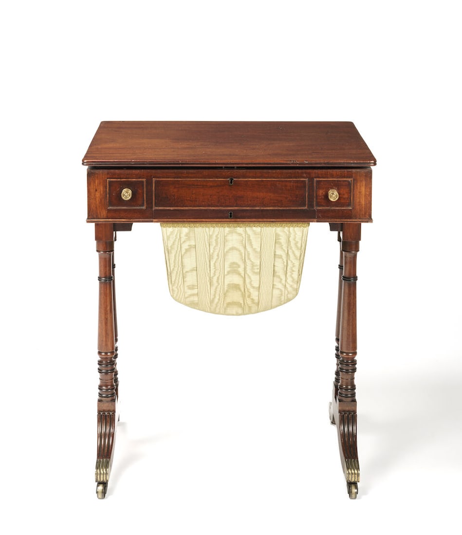 A REGENCY MAHOGANY WORK TABLE: A REGENCY MAHOGANY WORK TABLE The hinged rectangular lid enclosing a fitted writing interior above a stationery drawer and workbag lined in green ruched silk, raised on twin turned end supports and