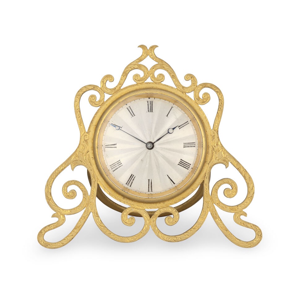 A small strut clock timepiece with pocket watch type movement: A small strut clock timepiece with pocket watch type movement The gilt case with pierced and engraved decoration supported by a simple strut folding from the back. The 1 inch silver engine turned