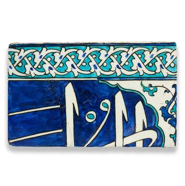 An Iznik calligraphic pottery tile Turkey, early 17th Century: An Iznik calligraphic pottery tile Turkey, early 17th Century of rectangular form, decorated underglaze in cobalt blue, turquoise and black on a white ground with partial inscription in thuluth in lob