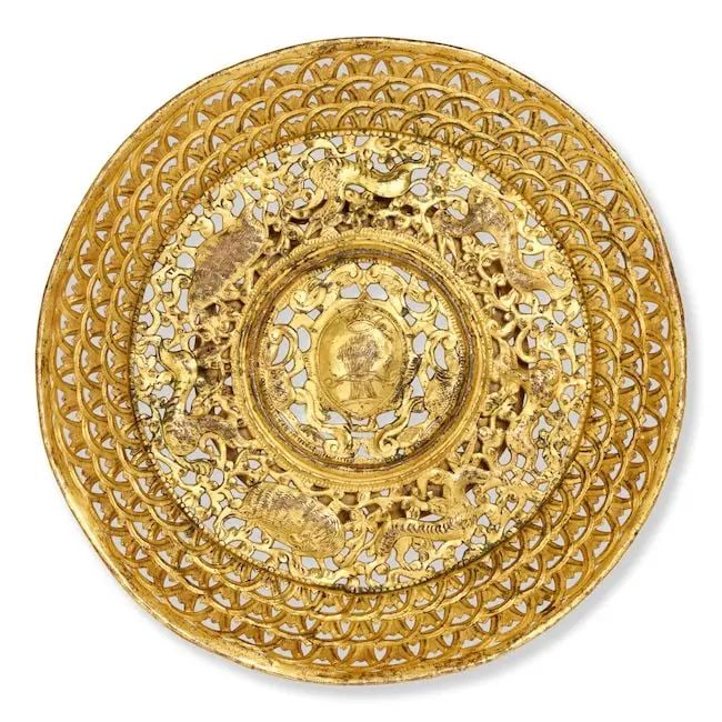 An Ottoman gilt-copper (tombak) dish Balkans, 17th/ 18th Century: An Ottoman gilt-copper (tombak) dish Balkans, 17th/ 18th Century of shallow rounded form on short, splayed foot with an openwork body, raised central boss engraved with wheatsheaf surmounted by crown,