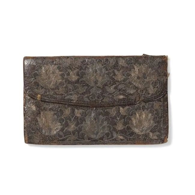 An Ottoman metal-thread embroidered leather wallet Turkey, early 18th Century: An Ottoman metal-thread embroidered leather wallet Turkey, early 18th Century of rectangular form with shaped flap, the brown morocco embroidered in silver and gilt thread with six floral rosettes to 