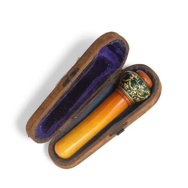 An enamelled-gilt-copper and amber huqqa mouthpiece for the Ottoman market Europe, late 19th Ce...: An enamelled-gilt-copper and amber huqqa mouthpiece for the Ottoman market Europe, late 19th Century comprising three amber components on a central wood pipe interspersed by a gilt-copper element deco