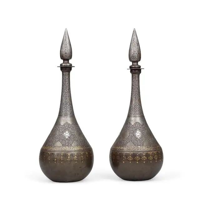 A pair of Qajar gold and silver-damascened steel bottles Persia, 19th Century(2): A pair of Qajar gold and silver-damascened steel bottles Persia, 19th Century of piriform with long tapering necks, flattened rims and removable pointed stoppers, the bodies and necks profusely engrav