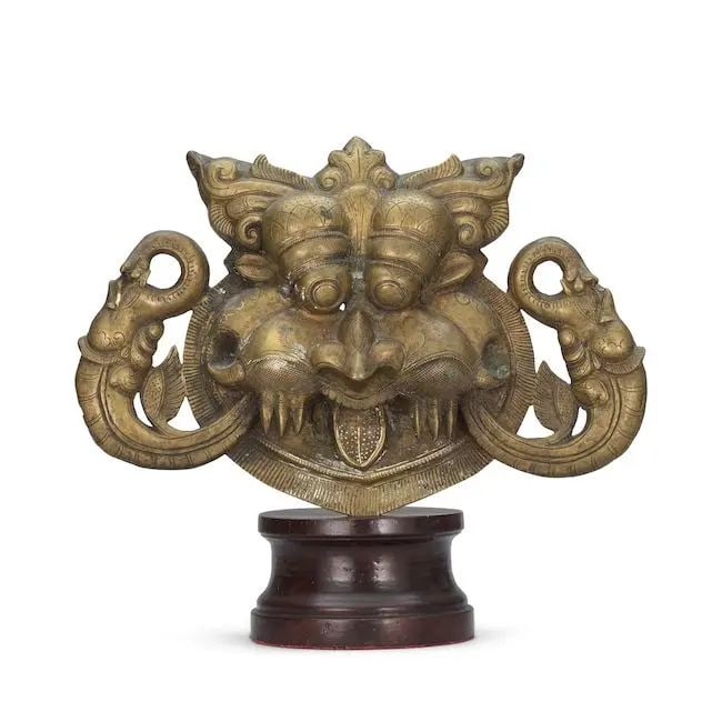 A large bronze Kirtimukha mask South India, probably Deccan, 18th Century: A large bronze Kirtimukha mask South India, probably Deccan, 18th Century with protruding eyes, short horns and open mouth with protruding fangs and tongue, flanked by elephant heads, engraved detail,