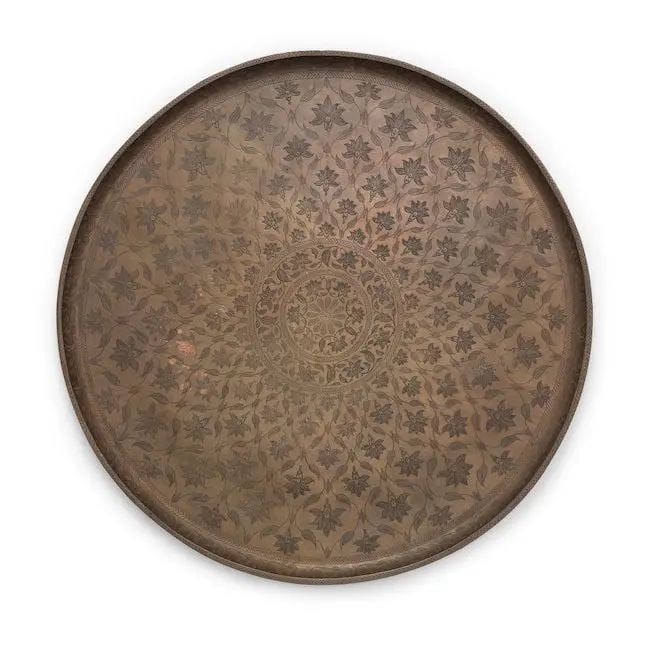 A Mughal engraved copper tray North India, late 17th Century: A Mughal engraved copper tray North India, late 17th Century of circular form with curved rim, profusely engraved with rosettes within within a lattice formed by foliate vines radiating from a central