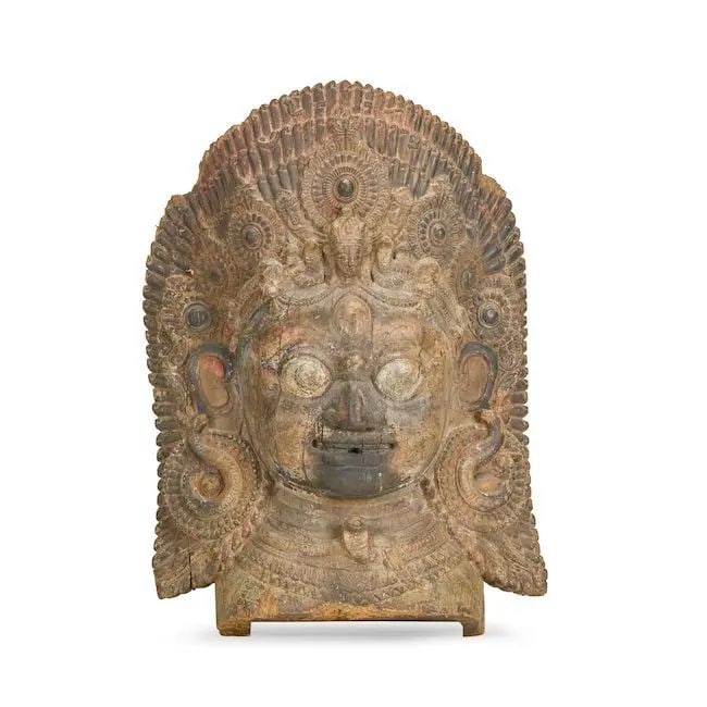 A large painted wood mask of Bhairava Nepal, Malla period, 16th Century: A large painted wood mask of Bhairava Nepal, Malla period, 16th Century depicted with ferocious expression, rotund face with wide mouth, bulging eyes and curling arched brows, flanked by earrings in t