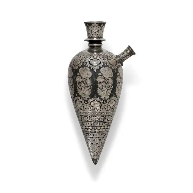 A silver-inlaid bidri huqqa base Deccan, 18th Century: A silver-inlaid bidri huqqa base Deccan, 18th Century of bulbous conical form, the flaring neck with raised ring, decorated in silver inlay with floral sprays and vegetal bands, lower body with peacoc
