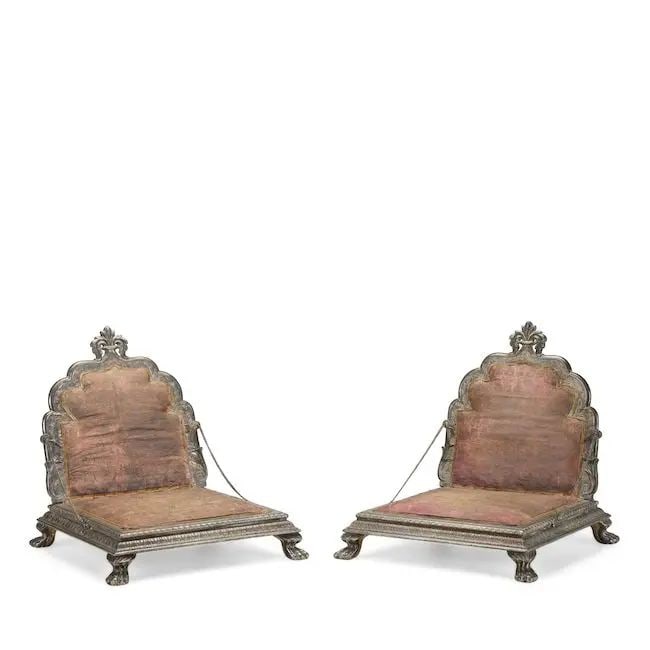 A pair of silver-mounted wood throne chairs (takht) North India, 19th Century(2): A pair of silver-mounted wood throne chairs (takht) North India, 19th Century each of square form on four lion-paw feet, the teak structures clad entirely in silver, the hinged cusped backs surmounted