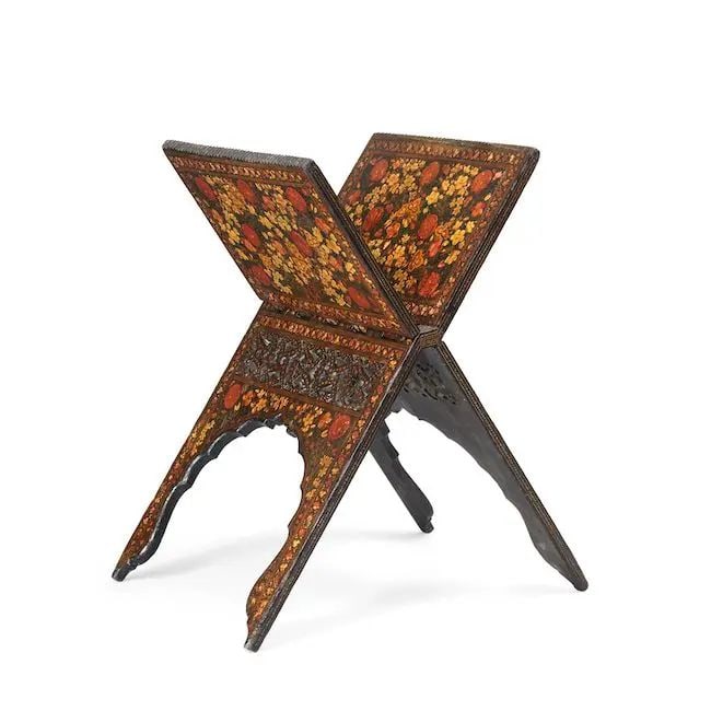 A Kashmir lacquered wood Qur'an stand India, 19th Century: A Kashmir lacquered wood Qur'an stand India, 19th Century of typical folding x-form with cusped arches to lower section and openwork panels below apex, the top with serrated edging, profusely decorate