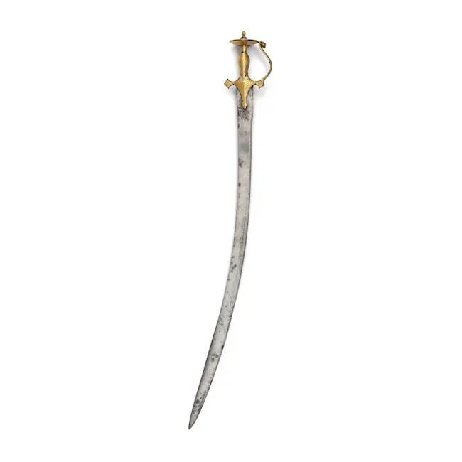 A gold-koftgari steel hilted sword (tulwar) Punjab, Lahore, 19th Century: A gold-koftgari steel hilted sword (tulwar) Punjab, Lahore, 19th Century the steel blade of curved form with flattened spine becoming double-edged towards the point, the hilt overlaid in sheet gold in