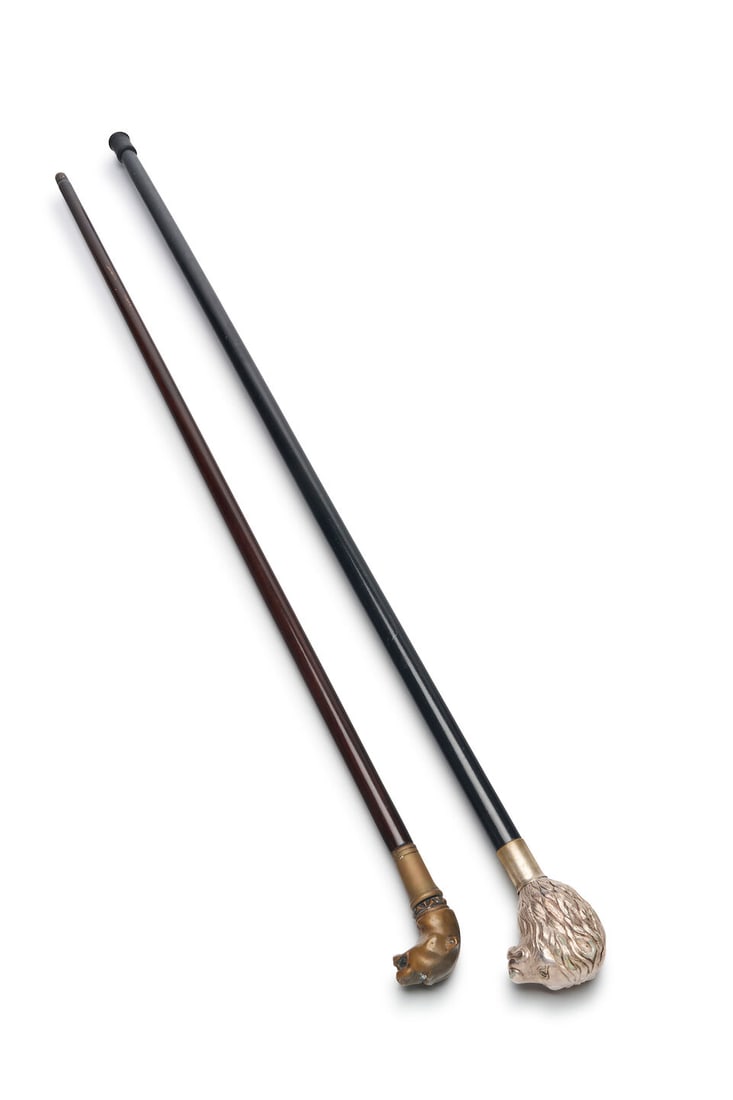 Two walking sticks with animal-head handles English, 20th century (2): Two walking sticks with animal-head handles English, 20th century the ebonised wooden walking stick with silver-plated lion's head, 99.0 cm long, the bronzed panther-head cane 94.0 cm long. (2) For fu