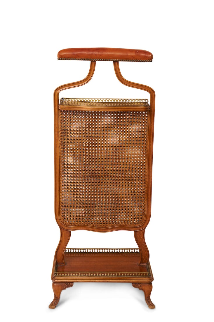 A vintage valet stand, stamped Herraiz Fecit stamped Herraiz Fecit: A vintage valet stand, stamped Herraiz Fecit stamped Herraiz Fecit with leather covered hanger, caned body and brass rail accents height: 112.0cm, width: 45.0cm For further information on this lot ple