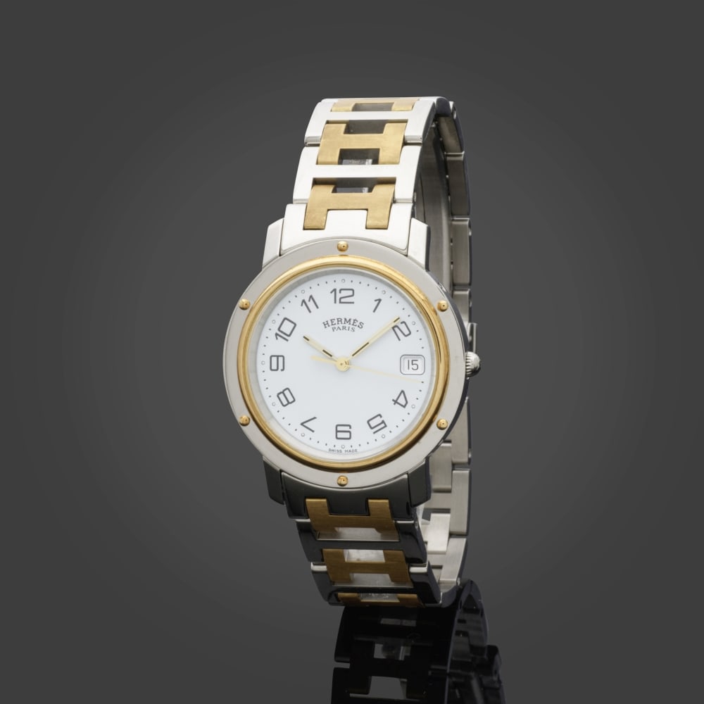Hermès Paris. Montre Clipper en acier inoxydable et métal doré. Hermès Paris...: Hermès Paris. Montre Clipper en acier inoxydable et métal doré. Hermès Paris. Clipper watch in stainless steel and gold-tone metal. Cadran blanc, mouvement à quartz. Chiffres 