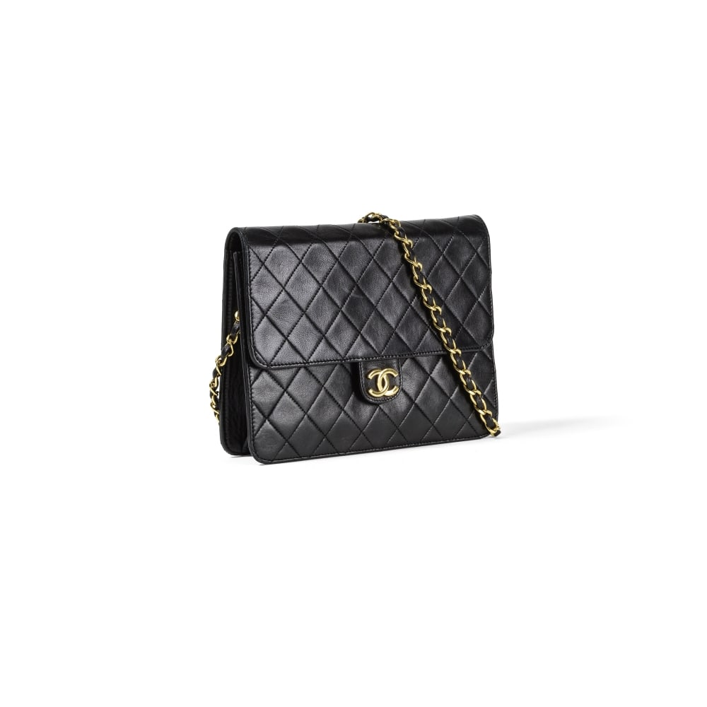 Chanel, circa 1990. Pochette Classique en cuir agneau matelassé noir. Chanel, circa 1990. C...: Chanel, circa 1990. Pochette Classique en cuir agneau matelassé noir. Chanel, circa 1990. Classic clutch in black quilted lambskin leather. Anse d'épaule en métal doré entrelac
