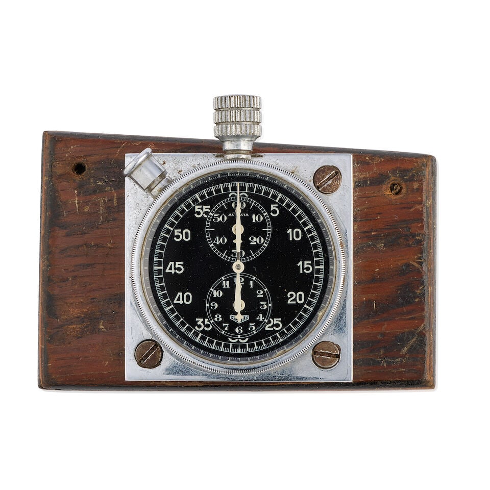 Heuer. A chrome plated manual wind dashboard clock Autavia , Circa 1933: Heuer. A chrome plated manual wind dashboard clock Model: Autavia Date: Circa 1933 Movement: Jewelled manual wind Dial: Black Case: Polished round, mounted on wood Signed: Case & dial Size: 10cm x 6cm